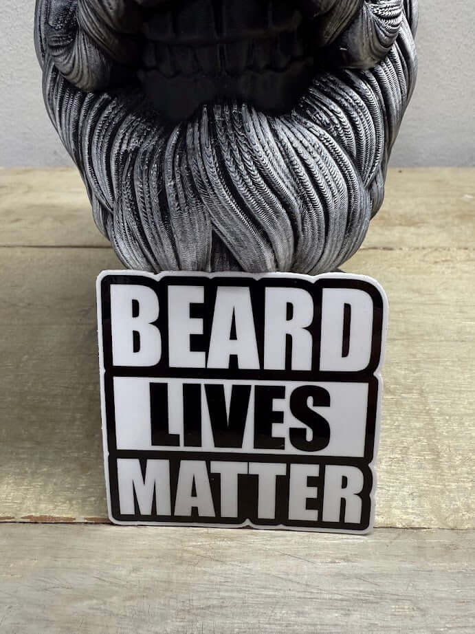 Beard Lives Matter 3-inch sticker on a wooden surface next to a skull figurine, showcasing beard pride in bold black-and-white design.