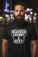 Man wearing a black t-shirt with 'Bearded Chubby & Sexy' text in an urban night setting.