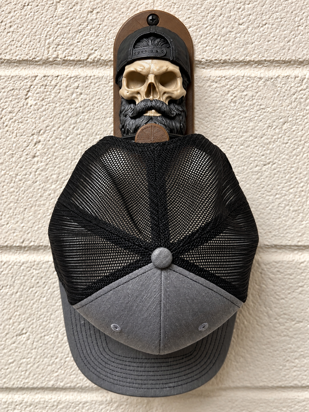 Bearded skull hat holder with black and gray cap displayed on a wall, showcasing unique 3D-printed design.