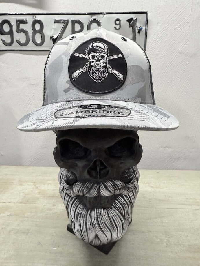 Bearded skull hunting trucker hat displayed on a skull, featuring a bold skull design with crossed axes.