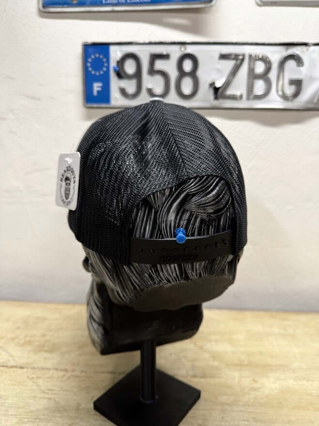 Back view of a black mesh trucker hat displayed on a mannequin head, showcasing its breathable design.