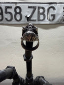 Bearded Skull Guy Men Stainless Steel Heavy Duty Ring displayed on a black holder with a vintage license plate in background.